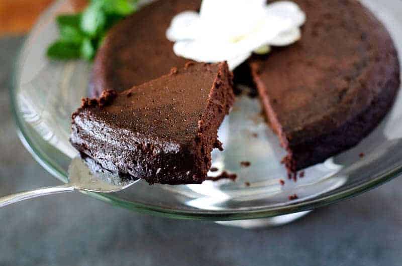 close up image of a cake server lifting a piece of cake off a cake stand