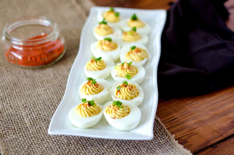 White tray on burlap runner with deviled eggs and paprika