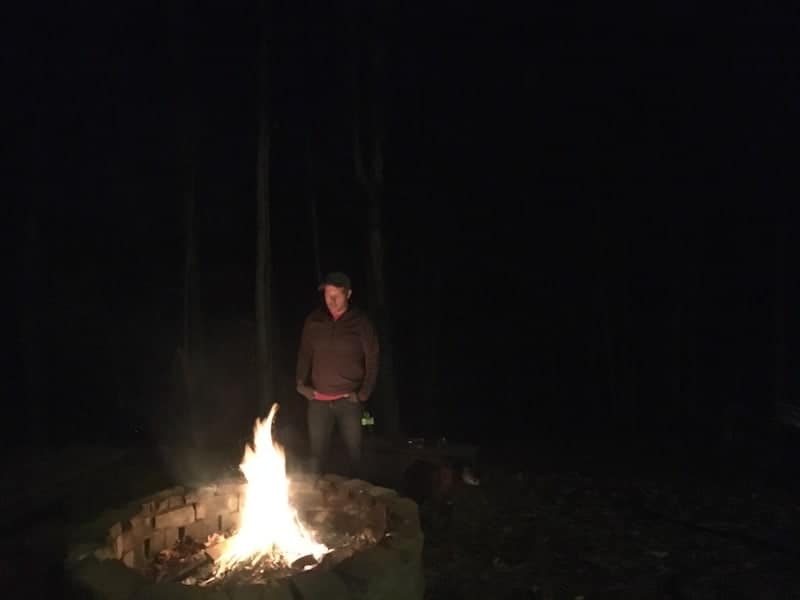 man standing over fire pit fire