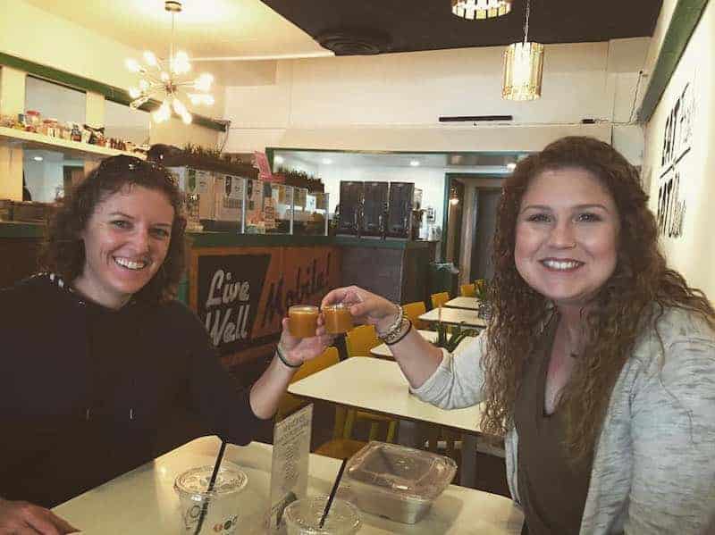 two women cheersing with energy shots in restaurant