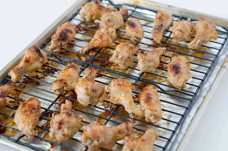 side view of baked chicken wings  on a wire rack on top of a baking sheet