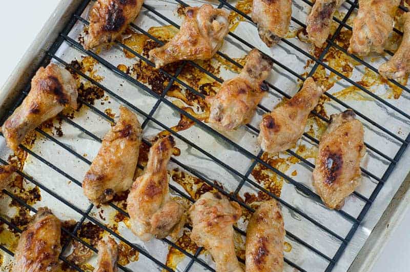 overhead view of baked chicken wings  on a wire rack on top of a baking sheet