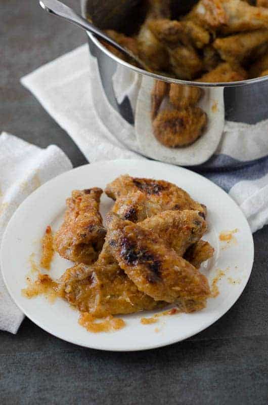 white plate with sweet and spicy whole30 chicken wings with pot in the background