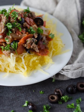 plate of spaghetti squash topped with pepperoni, sausage, black olives, and parsley