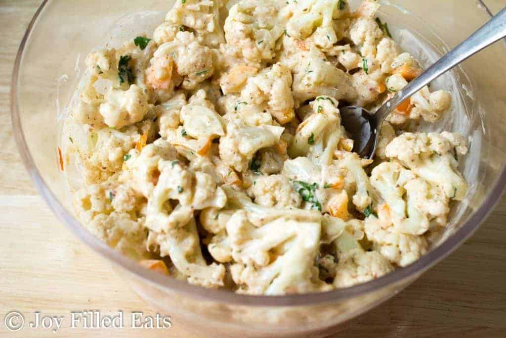 glass bowl full of cauliflower salad with serving spoon