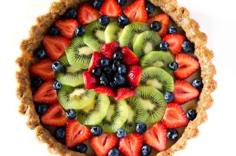 Overhead view of a paleo fruit tart topped with berries and kiwi