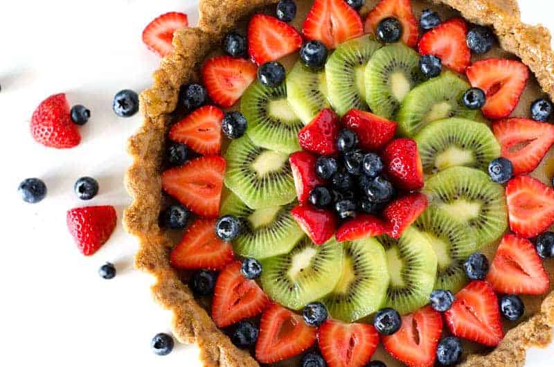 Overhead view of a paleo mixed fruit tart surrounded by berries