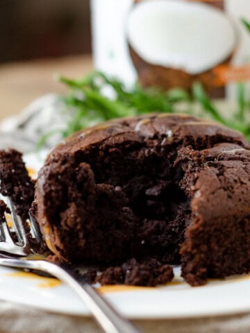 side view of personal mocha cake that has been cut into with a fork on the plate beside it