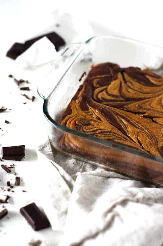 brownies in pan with broken chocolate on table