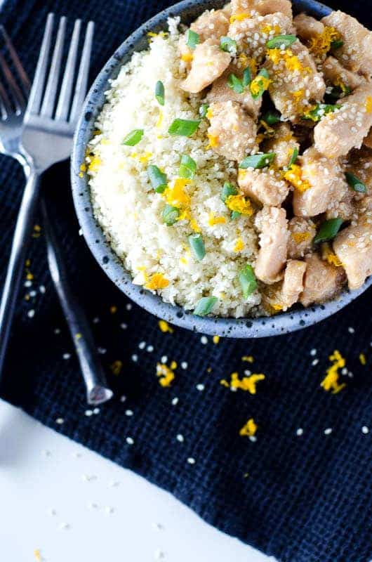 an overhead view of a bowl filled half with chicken and half with cauliflower rice