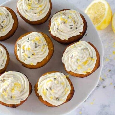 Overhead view of lemon lavender cupcakes on a cake stand with a lemon in the background