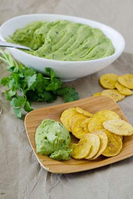 Side angle view of bowl of avocado dip with plate of chips