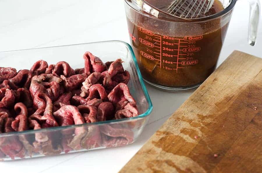 side angle view of raw meat in a pan getting ready to be marinated