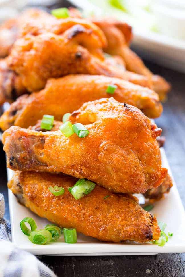 Close up side view of baked buffalo wings stacked on a plate