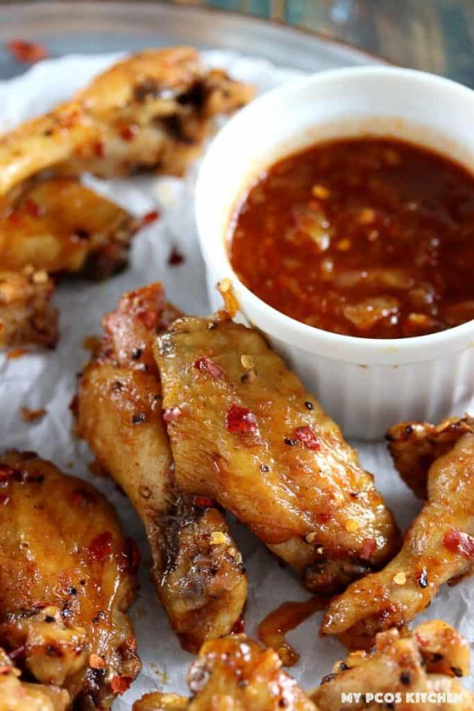 close up of thai chili chicken wings with bowl of dipping sauce