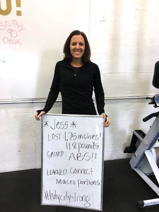 Woman holding whiteboard showing weight loss results from eating paleo macros