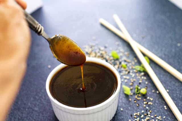 spoon with teriyaki sauce drizzling into a bowl of sauce