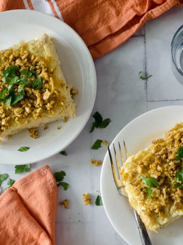 overhead view of two plates with pieces of chicken poppyseed casserole on them with orange napkins in the background