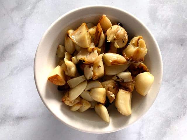 Overhead view of bowl full of roasted garlic cloves