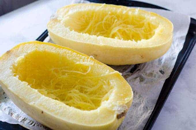 Two cooked halves of spaghetti squash face up with seeds scraped out