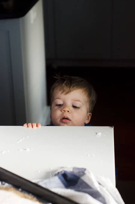 Little boy peeking over the edge of the table at a pan out of the shot