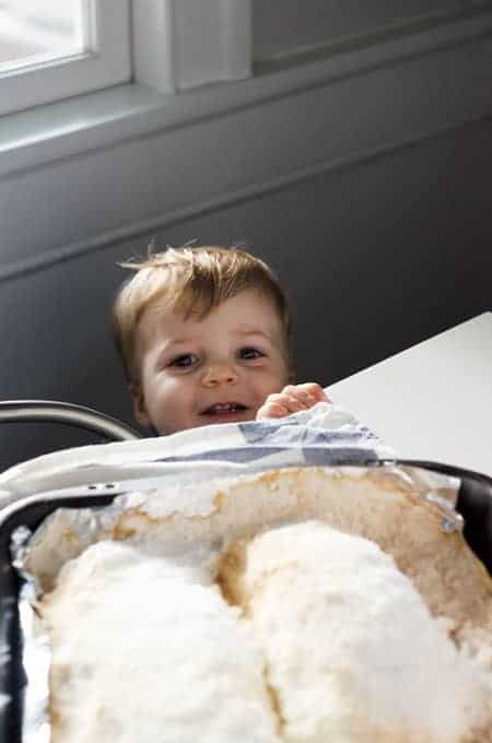 Salt baked fish on a sheet pan after baking, with a little boy smiling from below