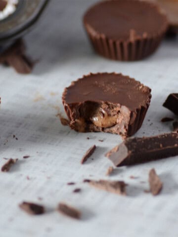 homemade chocolate almond butter cups on a counter with a bite out