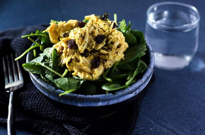 dark bowl of mixed greens salad topped with a scoop of curry cashew whole30 chicken salad