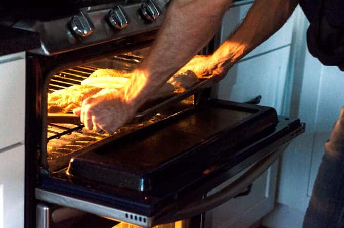 Man putting pan of pork belly into oven