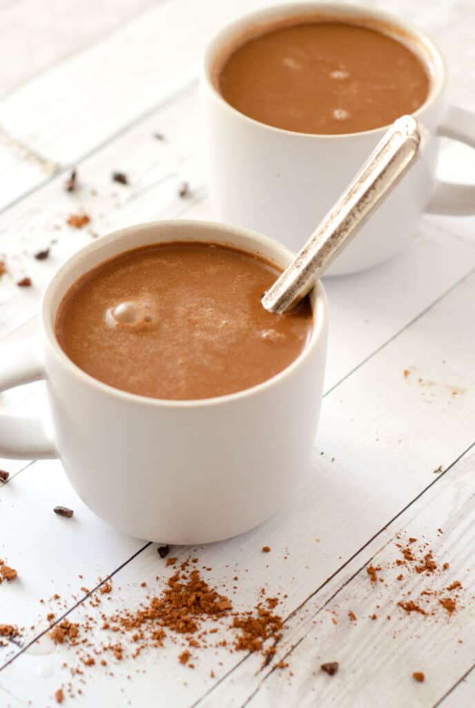 View of mug on table full of vegan hot cocoa with spoon in it