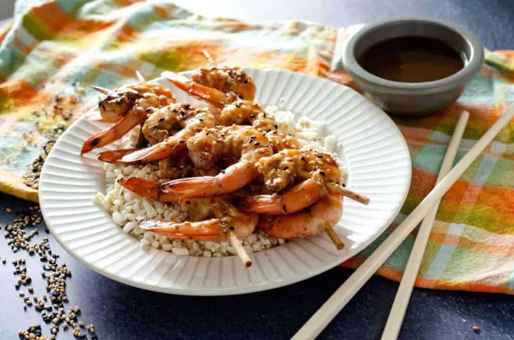 White plate with cauliflower rice and ginger teriyaki shrimp skewers 