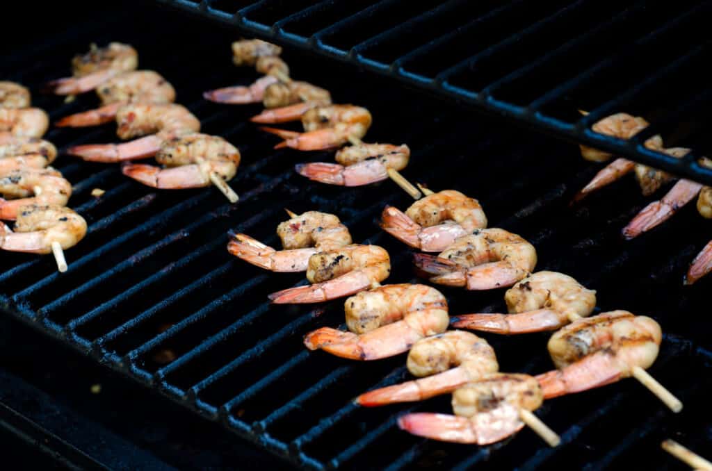 shrimp being cooked on skewers on grill