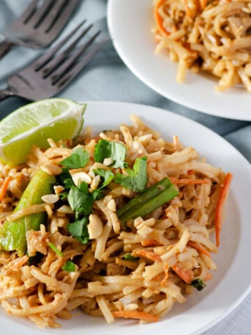 plate of homemade gluten free pad thai topped with green onions and forks in the background