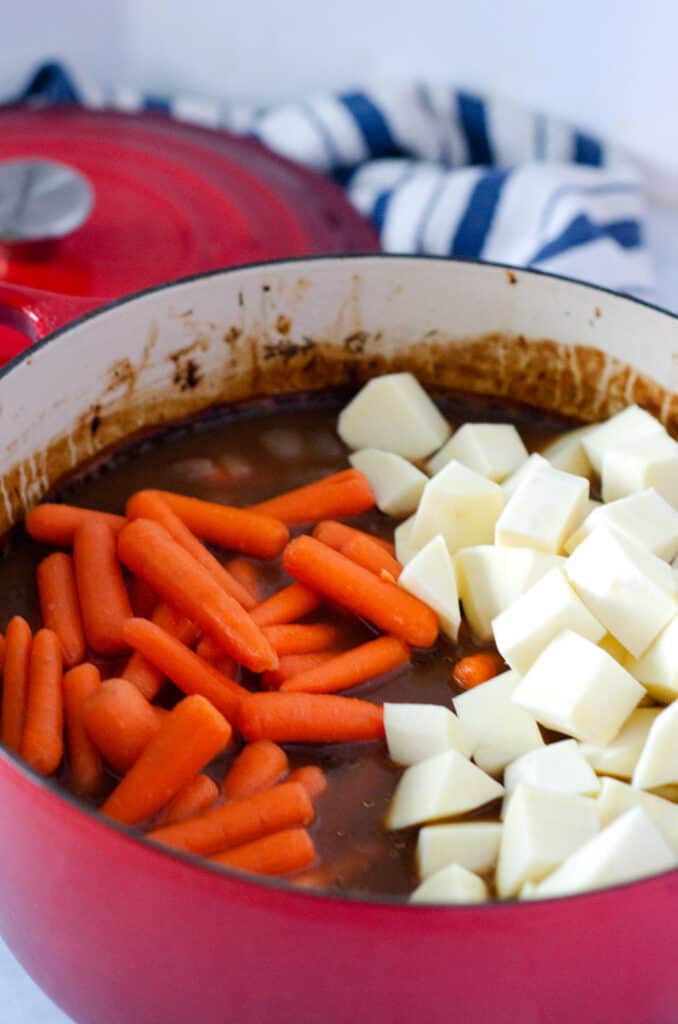 dutch oven full of beef stew with carrots and sweet potatoes