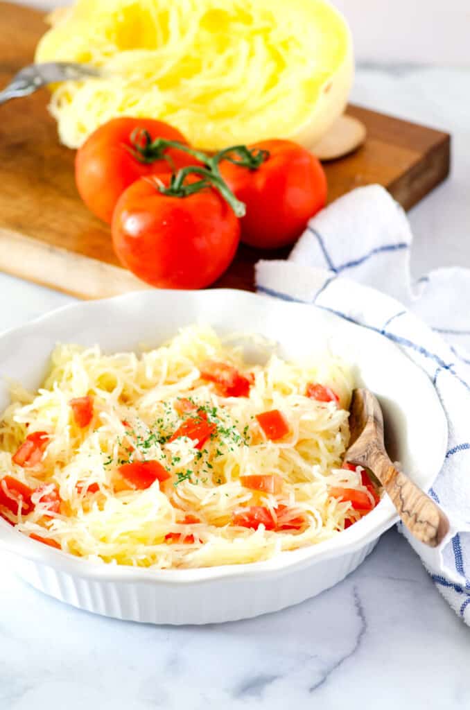 dish of spaghetti squash with tomatoes with cutting board in the background