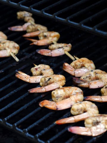 skewers of teriyaki shrimp on a black grill grate