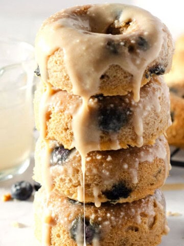 stack of grain free dairy free blueberry donuts topped with a vanilla glaze