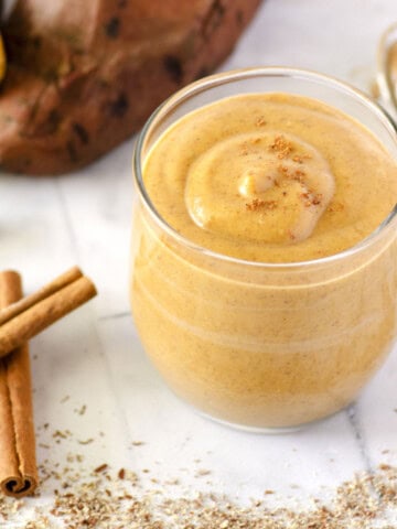 sweet potato smoothie with cinnamon sticks and a sweet potato in the background