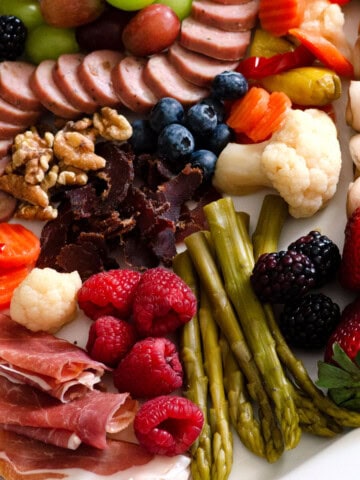 platter covered in meats, vegetables and fruits arranged artfully