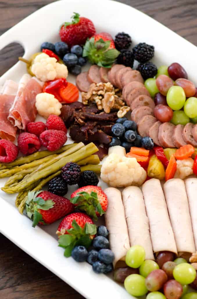 whole30 charcuterie board vertical view of meats, fruits and nuts on white platter