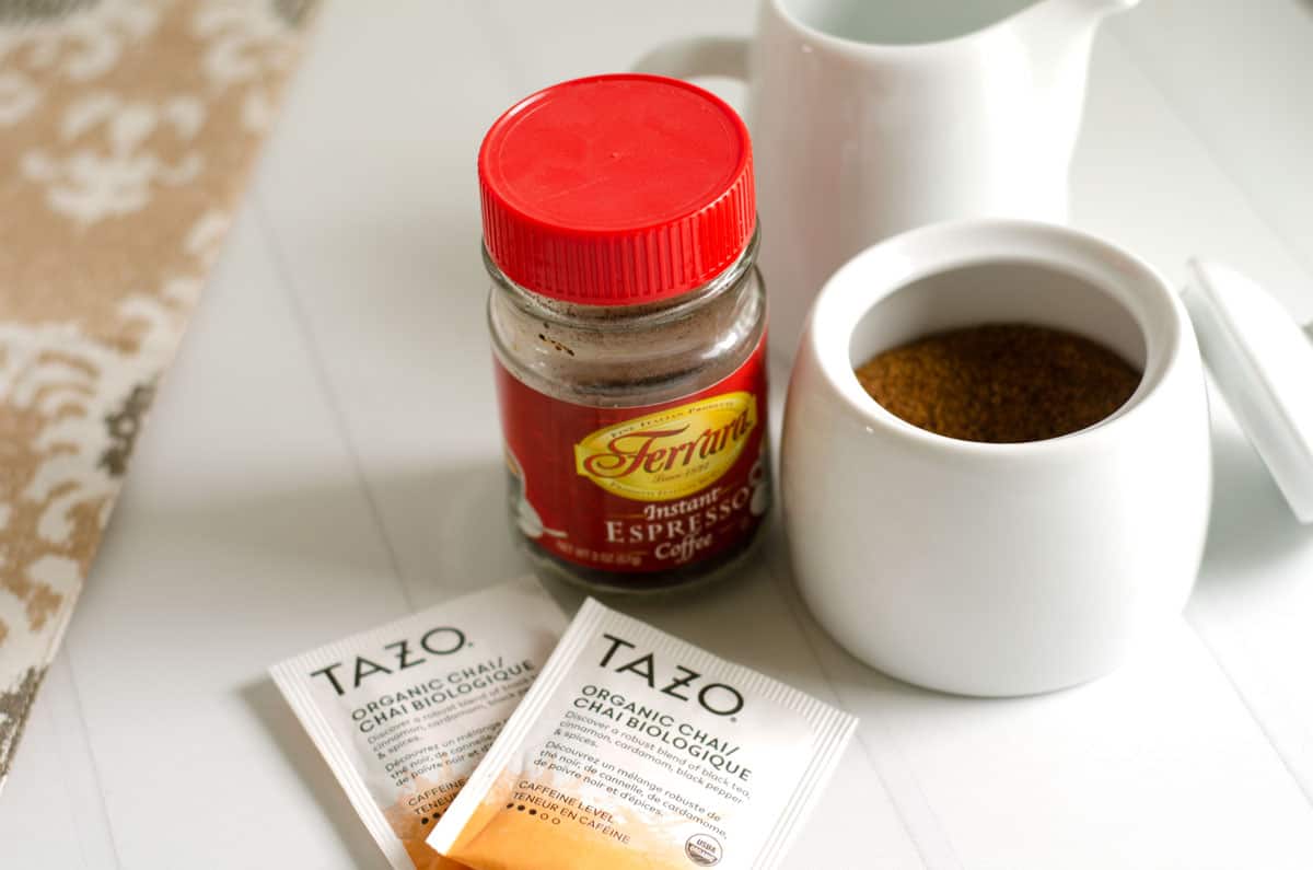 Dirty chai ingredients on a counter top - tea bags, espresso powder, coconut sugar and creamer