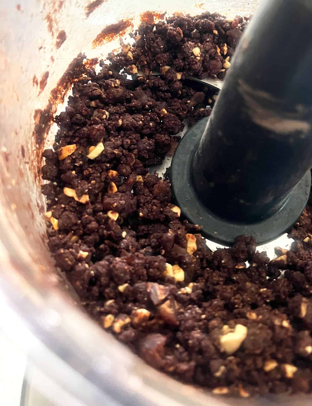 Close up view of paleo protein ball mixture in the food processor bowl with the blade