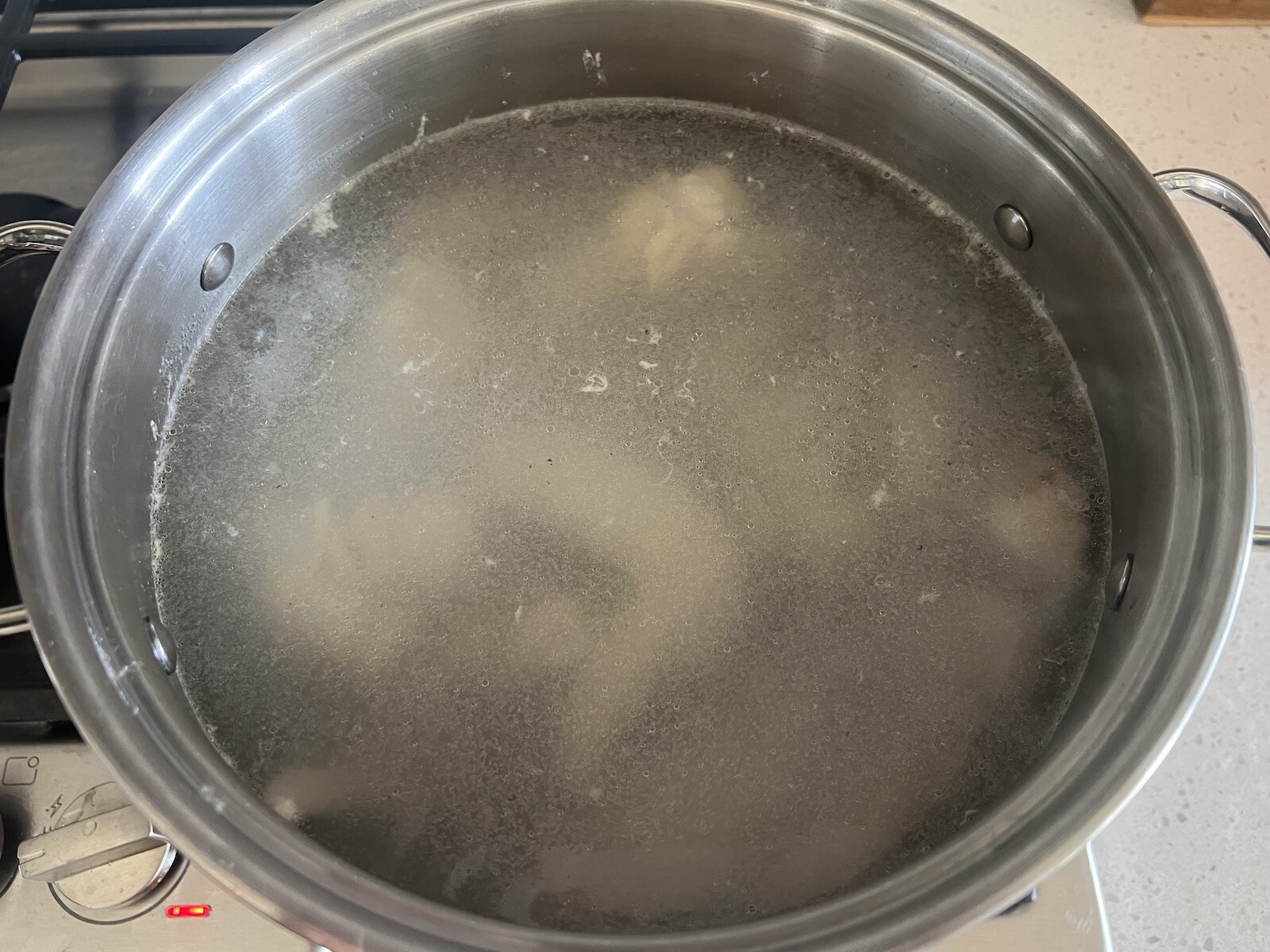 chicken wings covered in water in stockpot