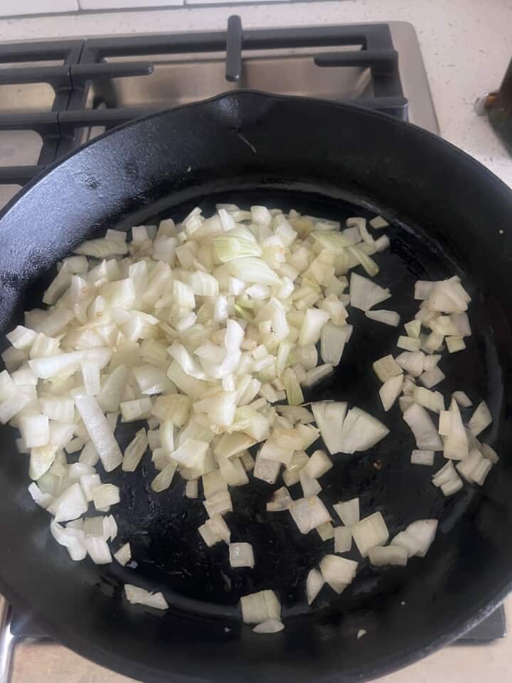 diced onion cooking in cast iron skillet