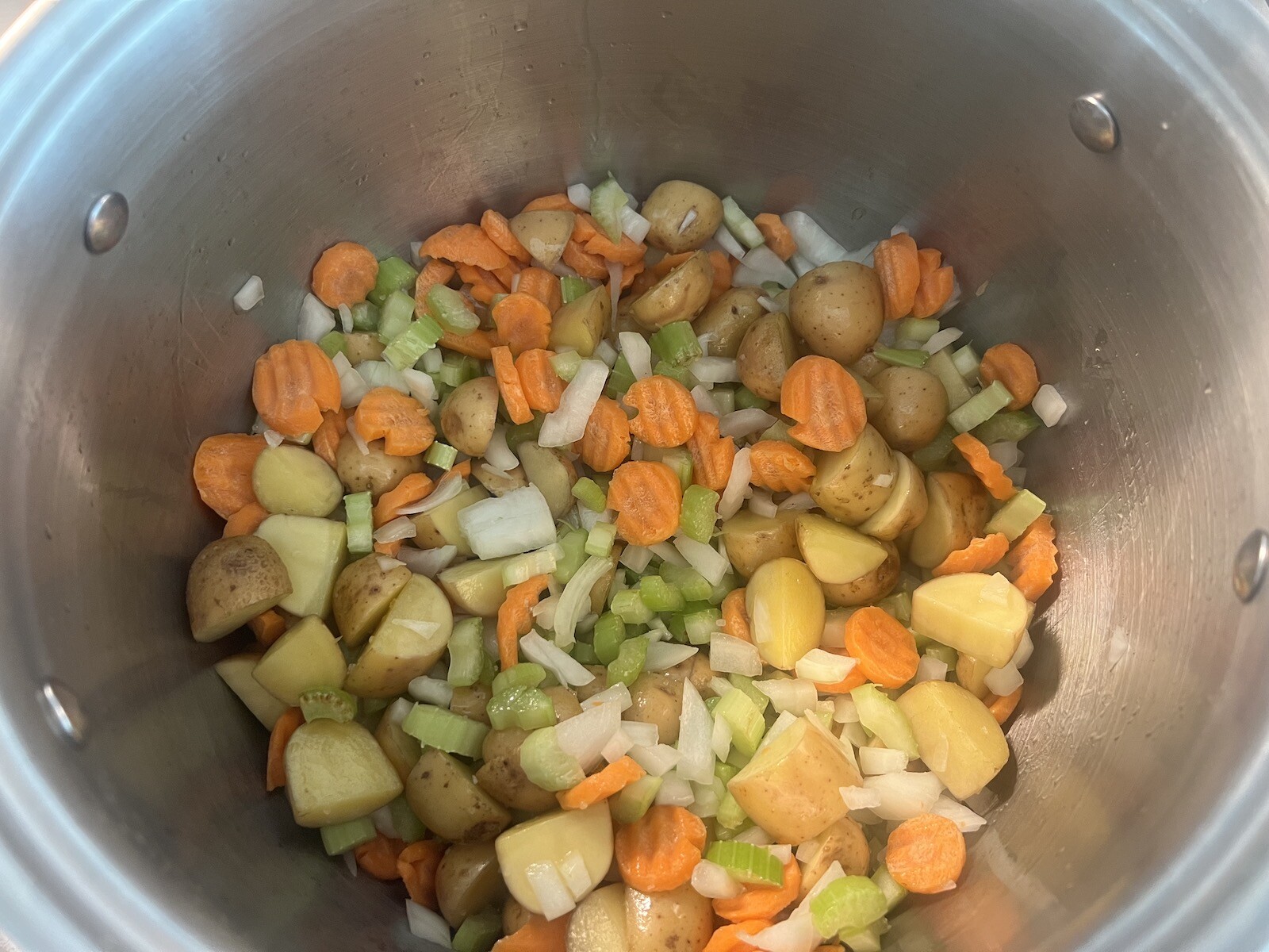 potatoes, celery, carrots, and onions sauteing in stockpot