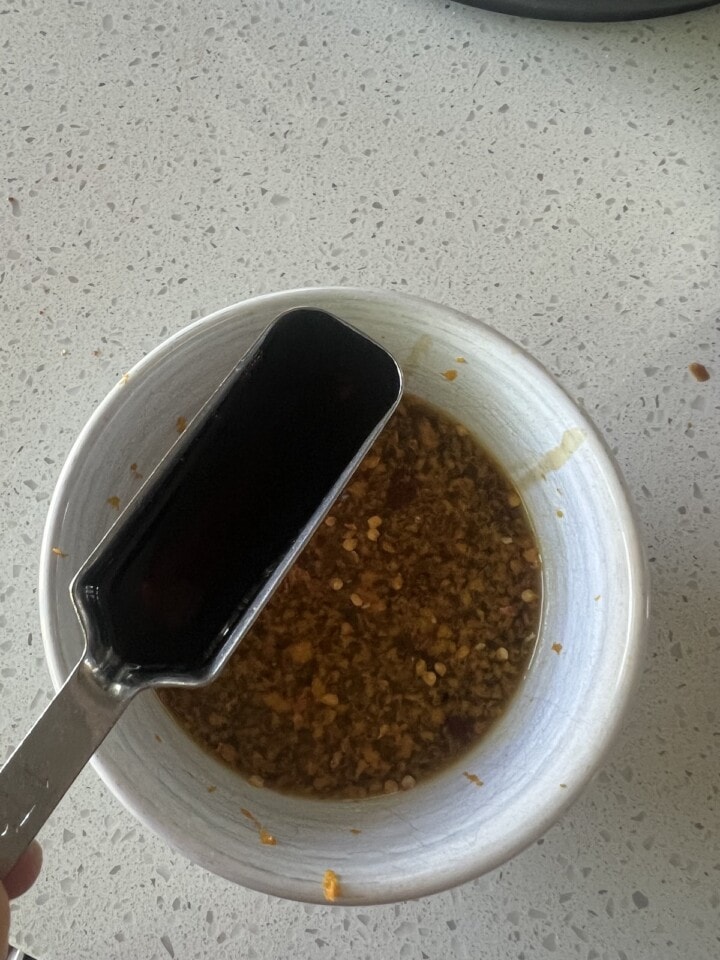 bowl of orange sauce with fish sauce being added