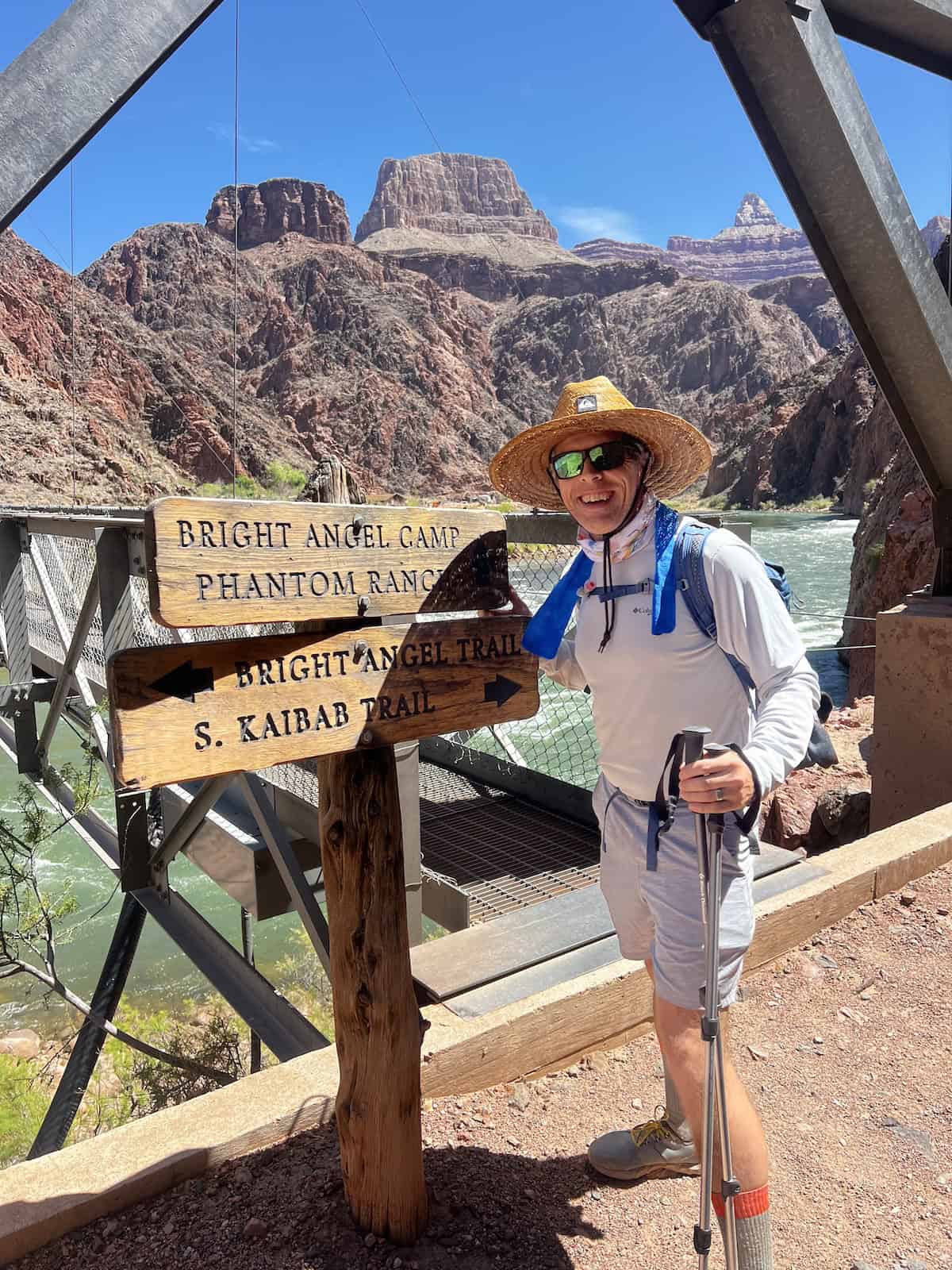 Man standing next to the signage at the grand canyon on the silver bridge