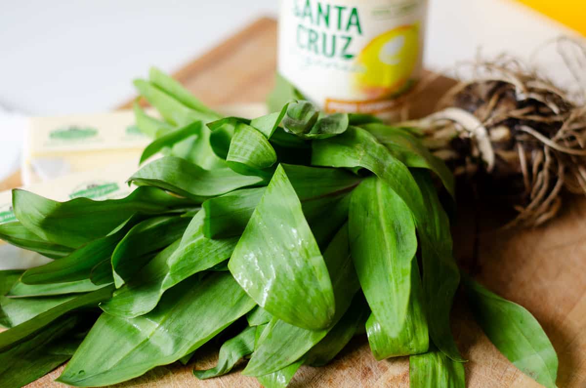 fresh ramps on a wooden cutting board with lemon juice and butter in the background