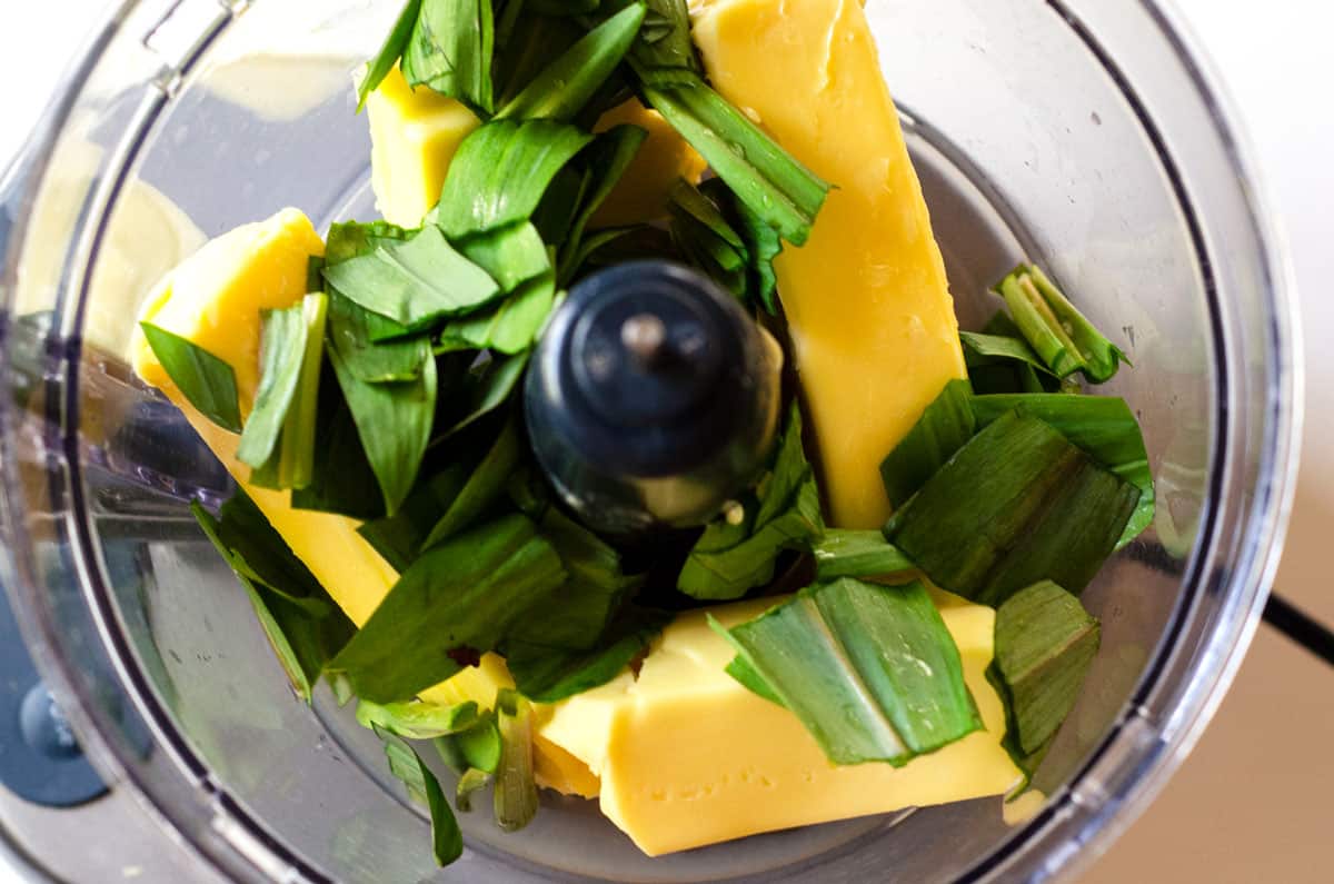 overhead view of butter and ramps in the bowl of a food processor