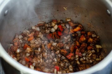 red bell pepper and white onion tossed with venison chili spices in the bottom of a stock pot